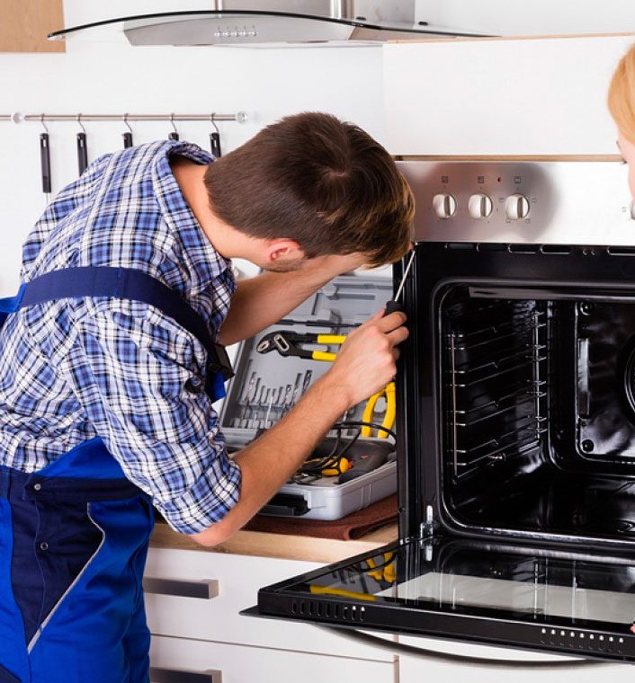 Technician working inside an open built in wall oven